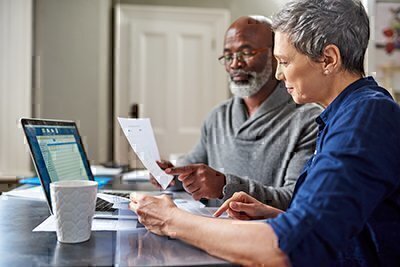 Man and woman sitting at computer, looking at papers