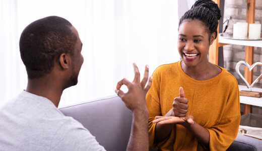 Man and woman sitting on a couch, signing to each other