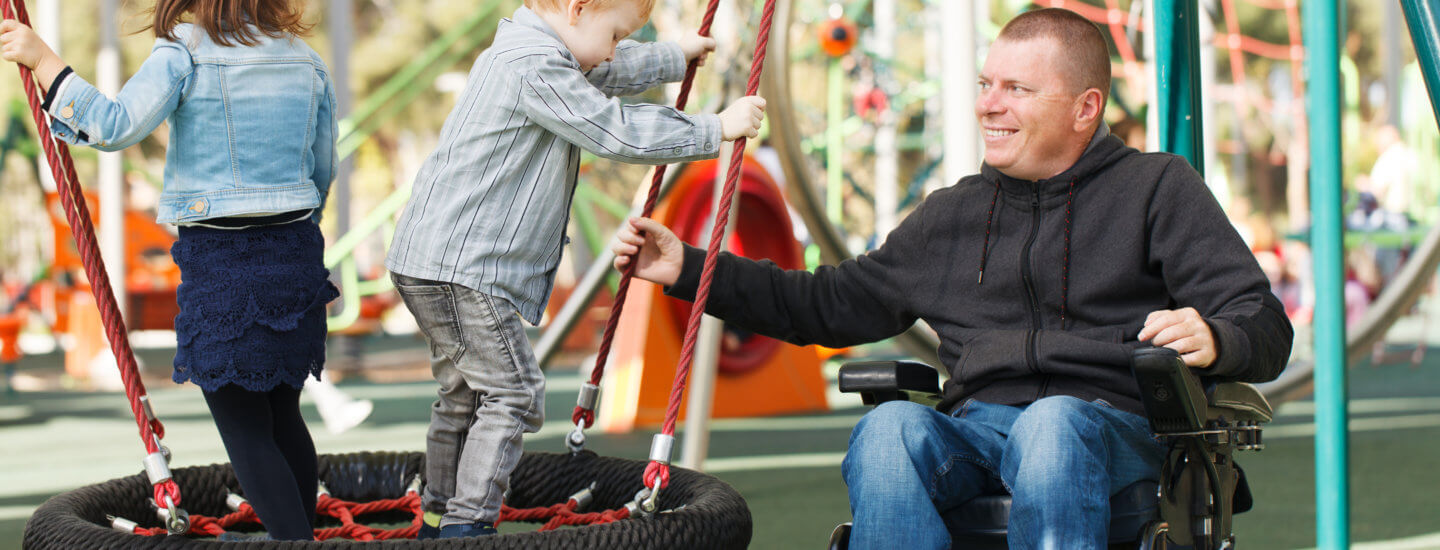 Man in wheelchair at park with children