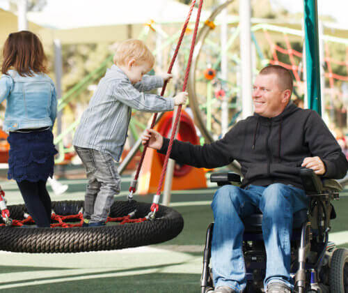 Man in wheelchair at park with children