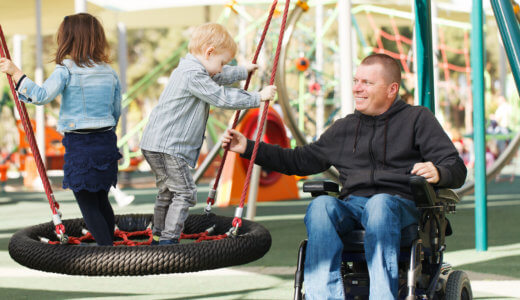 Man in wheelchair at park with children