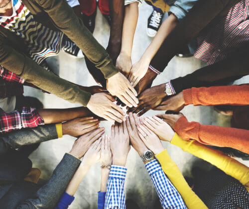 Group of people with their hands outstretched in a circle