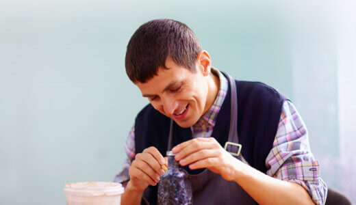 Young caucasian man building a sculpture in the shape of a bottle.