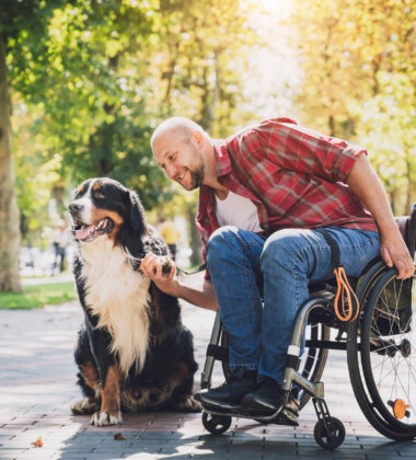 Happy young man with a physical disability who uses wheelchair with his dog